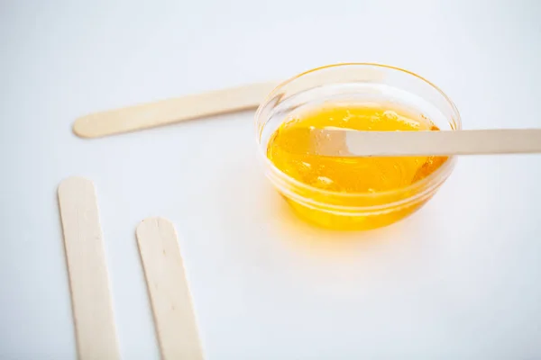 Waxing. Paste for sugaring in beauty salon. Concept depilation with wax and sticks on white background top view.