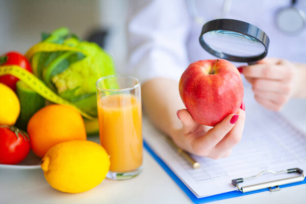 Diet. Doctor Nutritionist hold red apple in her office. Concept of natural food and healthy lifestyle. Fitness and healthy food diet concept. Balanced diet with vegetables.