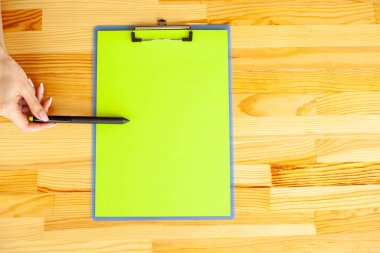 Bir klasörü bir yeşil renk kağıt ahşap masa arka plan üzerinde tutan office el. Boşaltmak. Metin için yer.