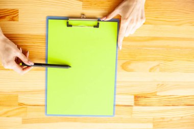 Bir klasörü bir yeşil renk kağıt ahşap masa arka plan üzerinde tutan office el. Boşaltmak. Metin için yer.