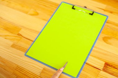 Bir klasörü bir yeşil renk kağıt ahşap masa arka plan üzerinde tutan office el. Boşaltmak. Metin için yer.