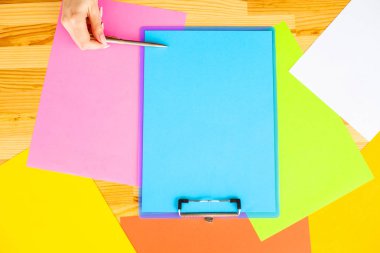 Bir klasörü bir mavi renk kağıt ve kalem ahşap masa renkli arka plan üzerinde tutan office el. Boşaltmak. Metin için yer.