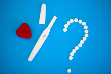 Sonuç olumlu olur. Hamilelik testi ve Doğum kontrol hapları Doğum kontrol kavramı mavi zemin üzerine yakın çekim.