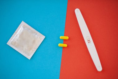 Hamilelik testi. Sonuç olumlu iki şeritler ve prezervatifle gebelik önleyici renkli arka plan, Doğum kontrol hapı, güvenli seks, sağlık concep.