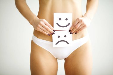 Kadın sağlık sorunu. Kadın üzgün gülen yüz midesini yakınındaki beyaz kartı tutan külot içinde uygun ince gövdeli closeup. Sindirim bozuklukları, adet ağrısı, sağlık sorunları kavramı.