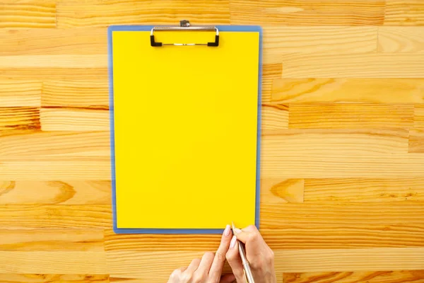 Boş klasör sarı kağıt ile. Bu Holding klasöre el ve ahşap arka plan üzerinde. Boşaltmak. Metin için yer.