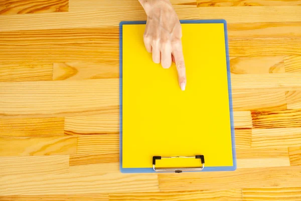 Boş klasör sarı kağıt ile. Bu Holding klasöre el ve ahşap arka plan üzerinde. Boşaltmak. Metin için yer.