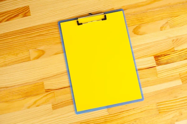 Blank Folder with Yellow Paper. Hand that Holding Folder and Handle on Wood Background. Copyspace. Place for Text.