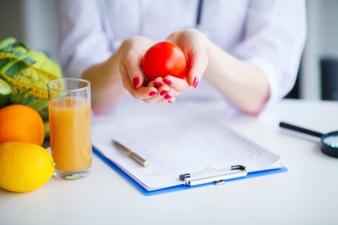 Diyet. Beslenme uzmanı doktor ofisinde domates tutun. Kavramı doğal gıda ve sağlıklı bir yaşam tarzı. Fitness ve sağlıklı gıda diyet kavramı. Dengeli beslenme sebze ile.