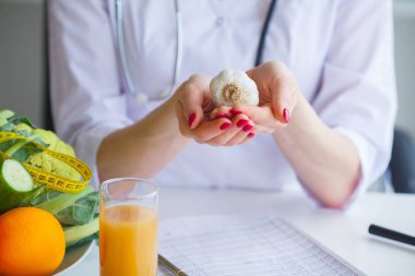 Diyet. Beslenme uzmanı doktor ofisinde sarımsak tutun. Kavramı doğal gıda ve sağlıklı bir yaşam tarzı. Fitness ve sağlıklı gıda diyet kavramı. Dengeli beslenme sebze ile.