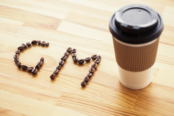 Good Morning. Coffee Time. Coffee to go and beans on a wooden background.