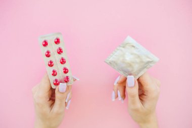 Doğum kontrolü. Doğum kontrol hapları ve unwrapped bir prezervatif. Renkli hap ve kapsül pembe bir arka plan üzerinde. Eczane tema, kapsül hap ilaç antibiyotik paketleri ile.