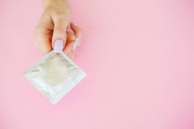 Doğum kontrolü. Doğum kontrol hapları ve unwrapped bir prezervatif. Renkli hap ve kapsül pembe bir arka plan üzerinde. Eczane tema, kapsül hap ilaç antibiyotik paketleri ile.