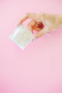 Doğum kontrolü. Doğum kontrol hapları ve unwrapped bir prezervatif. Renkli hap ve kapsül pembe bir arka plan üzerinde. Eczane tema, kapsül hap ilaç antibiyotik paketleri ile.