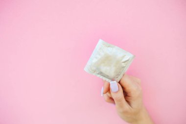 Doğum kontrolü. Doğum kontrol hapları ve unwrapped bir prezervatif. Renkli hap ve kapsül pembe bir arka plan üzerinde. Eczane tema, kapsül hap ilaç antibiyotik paketleri ile.