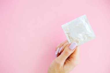 Doğum kontrolü. Doğum kontrol hapları ve unwrapped bir prezervatif. Renkli hap ve kapsül pembe bir arka plan üzerinde. Eczane tema, kapsül hap ilaç antibiyotik paketleri ile.