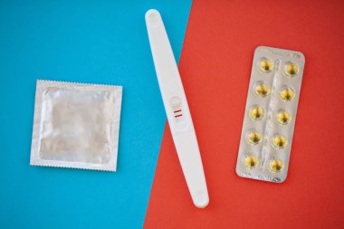 Hamilelik testi. Sonuç olumlu iki şeritler ve prezervatifle gebelik önleyici renkli arka plan, Doğum kontrol hapı, güvenli seks, sağlık concep.