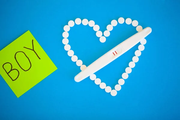 The result is positive. Close up of pregnancy test and contraceptive pills birth control concept on blue background.