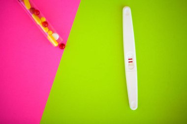 Hamilelik testi. Sonuç olumlu iki şeritler ve prezervatif gebelik önleyici renkli arka plan, Doğum kontrol hapı, güvenli seks, sağlık kavramı ile.