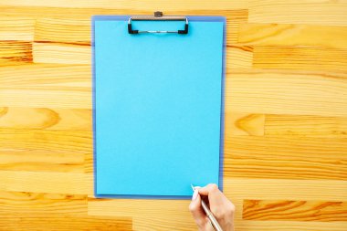 Bir klasörü bir mavi renk kağıt ahşap masa arka plan üzerinde tutan office el. Boşaltmak. Metin için yer.