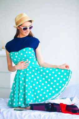 Tatil. Geri kalanı için hazırlanıyor olan kadın. Genç güzel kız yatakta oturur. Gülümseyen bir kadın portresi. Mutlu kız tatile gider.