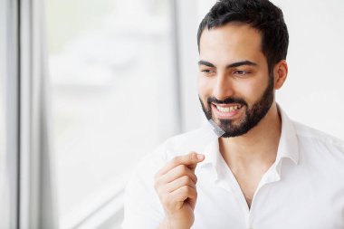 Diş beyazlatma. Şerit beyazlatma tutan güzel gülümseyen kadın. Yüksek çözünürlüklü görüntü.