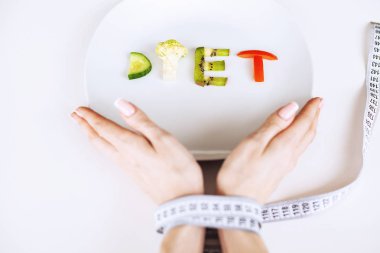 Beslenme veya kilo kontrolü kavramı. Santimetre teyp ve metin eklemek için bir yer ile beyaz bir arka plan üzerinde çatalı. Sağlık, kilo kaybı, diyet, doğru beslenme kavramı.