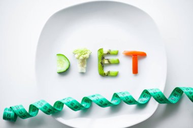 Beslenme veya kilo kontrolü kavramı. Santimetre teyp ve metin eklemek için bir yer ile beyaz bir arka plan üzerinde çatalı. Sağlık, kilo kaybı, diyet, doğru beslenme kavramı.