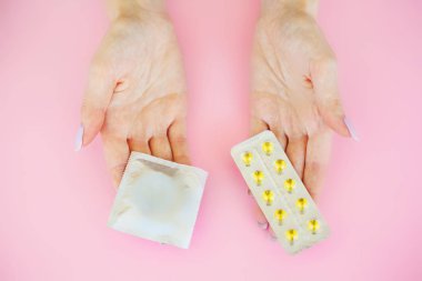 Doğum kontrolü. Doğum kontrol hapları ve unwrapped bir prezervatif. Renkli hap ve kapsül pembe bir arka plan üzerinde. Eczane tema, kapsül hap ilaç antibiyotik paketleri ile.
