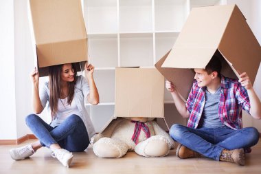 Genç bir çift yeni evinde karton kutuları açıyor. Taşınan ev.