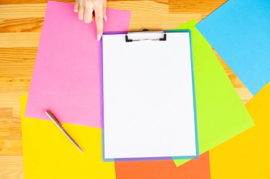 Bir klasörü bir mavi renk kağıt ve kalem ahşap masa renkli arka plan üzerinde tutan office el. Boşaltmak.