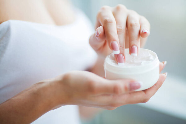 Уход за кожей рук. Крупным планом женских рук, держащих сливочную трубку, красивые женские руки с натуральными ногтями маникюра применения косметического крема для рук на мягкой шелковистой здоровой коже
.