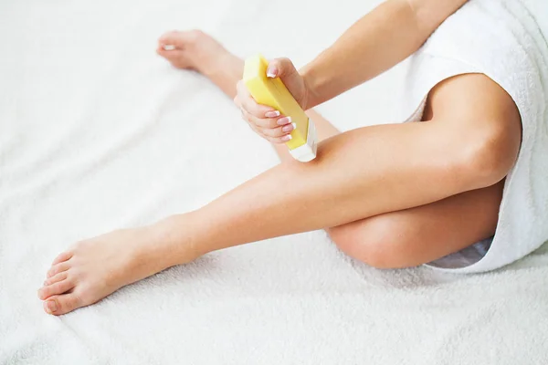 Women receive waxing for hair removal in her bathroom.
