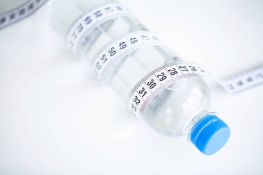 Diyet kavramı. Şişe beyaz mutfak masasında ölçü bandı ile.