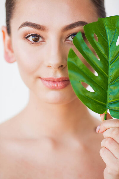 Skincare. Beautiful Woman Portrait on White Background With Clean Skin and Green Leaf in Hand.