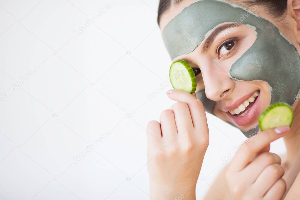 Skin Care. Young Woman With Cosmetic Clay Mask Holding Cucumber At Her Bathroom.