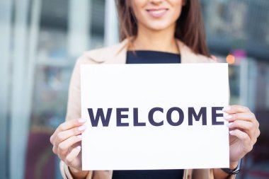 Women business with the poster with welcome message. clipart