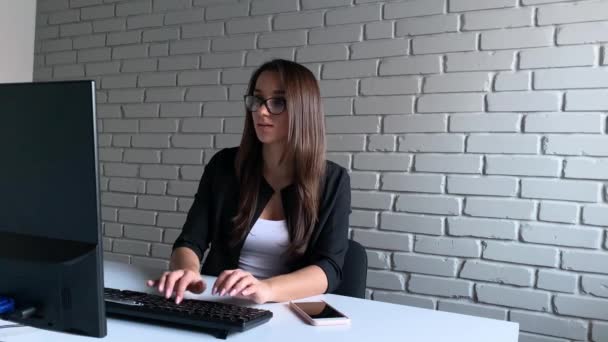 Donna d'affari seduta alla scrivania e che utilizza il suo computer portatile ed esprime successo in un ambiente di ufficio — Video Stock