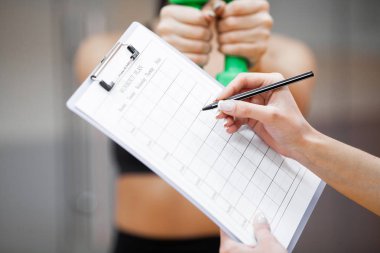 Fitness planı. Yakın çekim spor eğitmeni tutarlar için egzersiz planı