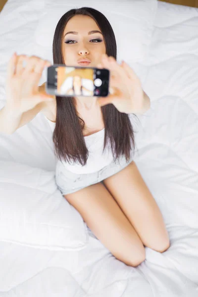 Buenos días. Joven mujer feliz tomando selfie con teléfono móvil en la mañana dormitorio — Foto de Stock