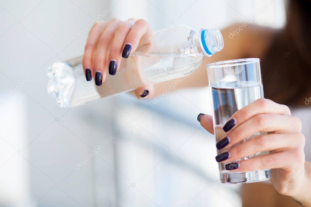 Young woman drinking water. Beautiful young girl holding bottle of water.