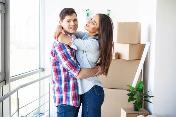 Nuevo hogar. Divertida pareja joven disfrutar y celebrar mudarse a un nuevo hogar. Pareja feliz en la habitación vacía de nuevo hogar — Foto de Stock