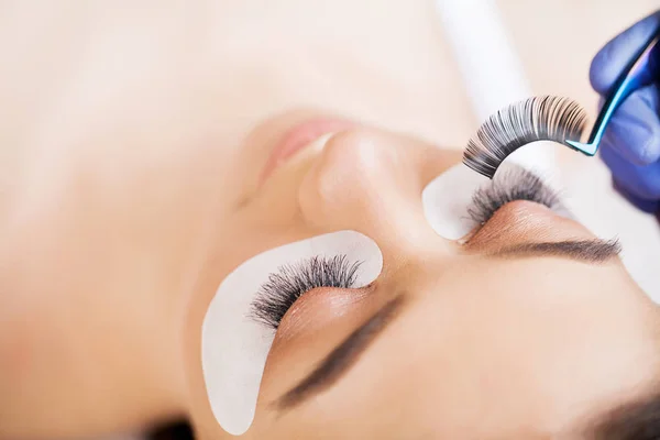 Eyelashes extensions. Fake Eyelashes. Eyelash Extension Procedure. Professional stylist lengthening female lashes. Master and a client in a beauty salon — Stock Photo, Image