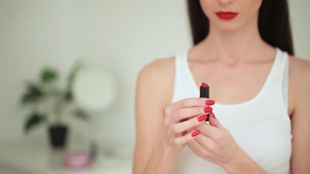 Beautiful young woman putting lipstick on lips — Stock Video