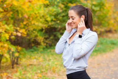 Neşeli Fitness kadın 30'lu Bluetooth Earpod dokunmadan ve Green Park'ta dinlenme sırasında cep telefonu, tutan spor giyim fotoğrafı