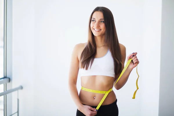 Donna che misura la vita dopo l'allenamento. Mani che misurano la vita con un nastro. Donna magra e sana — Foto Stock