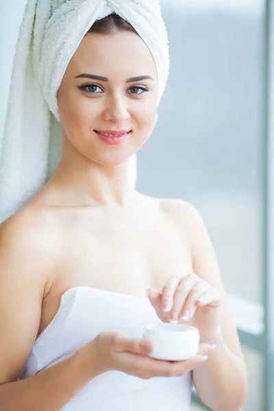 Eine schöne Frau, die ein Hautpflegeprodukt, Feuchtigkeitscreme oder Lotion verwendet und sich um ihren trockenen Teint kümmert. Feuchtigkeitscreme in weiblichen Händen — Stockfoto