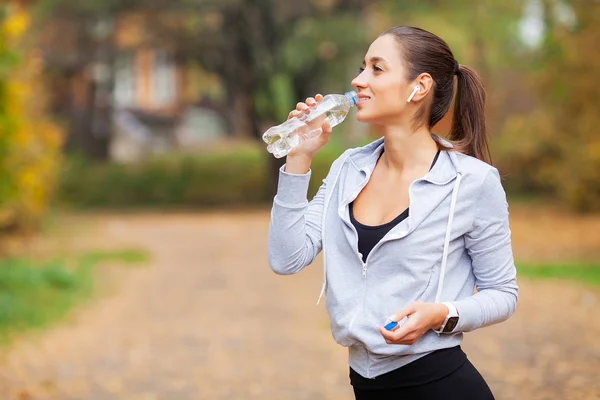 Deportes al aire libre. Mujer bebiendo agua después de correr — Foto de Stock