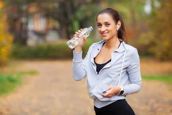 Спорт на открытом воздухе. Женщина пьет воду после бега — стоковое фото