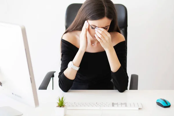 Head pain. Exhausted young woman feeling pain in head after working on computer. Overwork concept